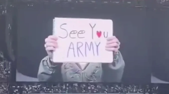 Jin de BTS brandit une pancarte "See You Army" à Paris